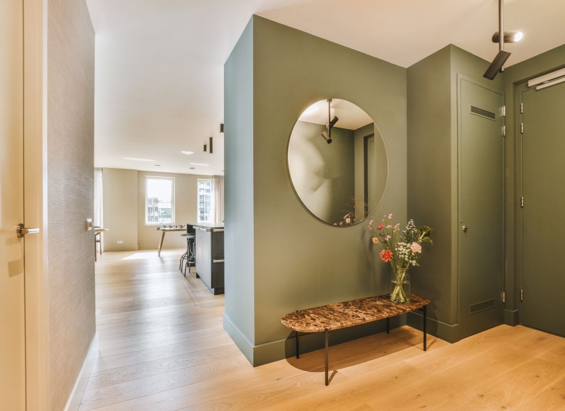 prikaz eleganto sređenog hodnika zelene boje sa ogledalom i modernom klupom za sedenje