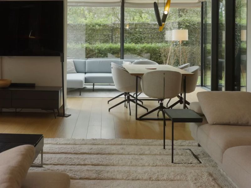 prikaz dnevne sobe sa televizorom, stolom i stolicama za ručavanje i tepihom